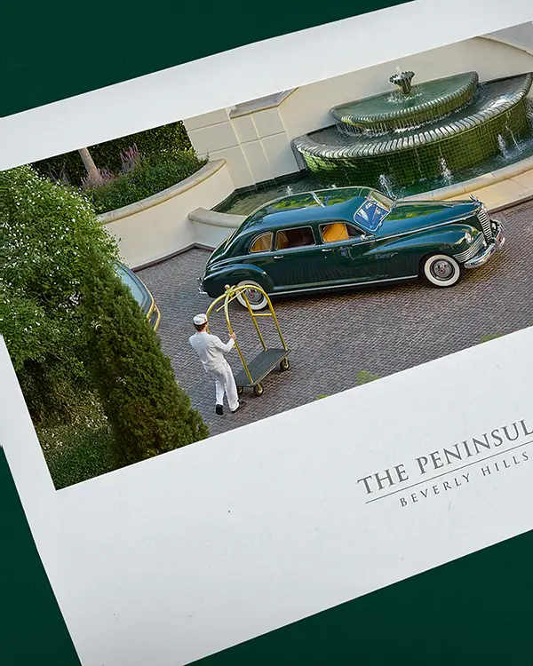 green vintage car arriving at The Peninsula Beverly Hills as hotel staff wait nearby